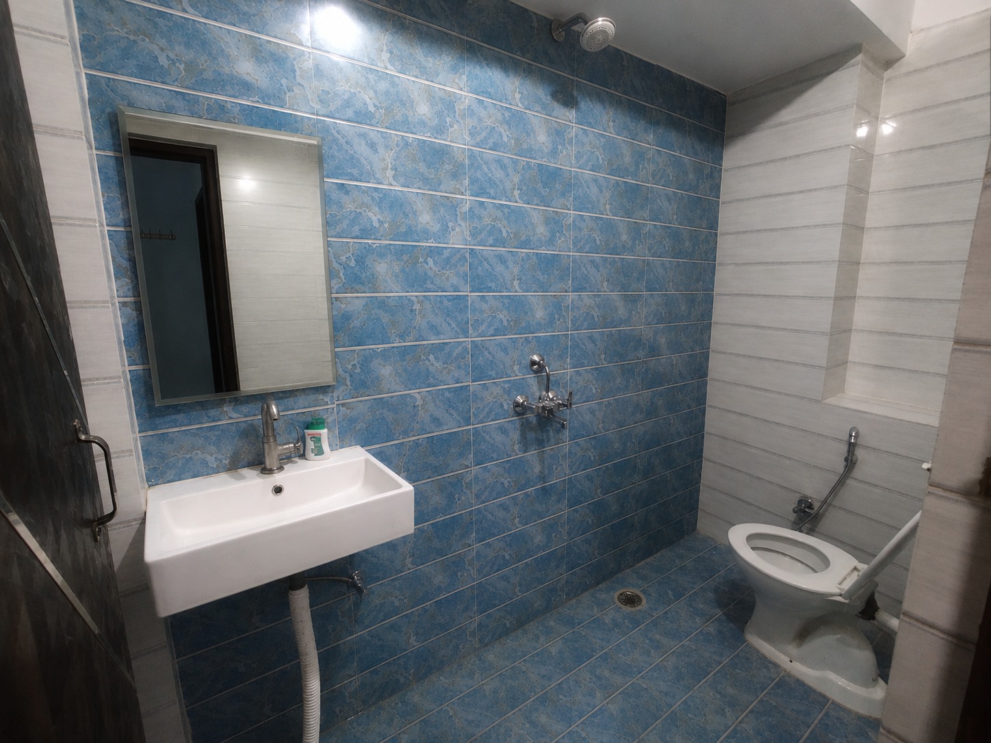 Delux bathroom tiled in blue with a mirror and shower