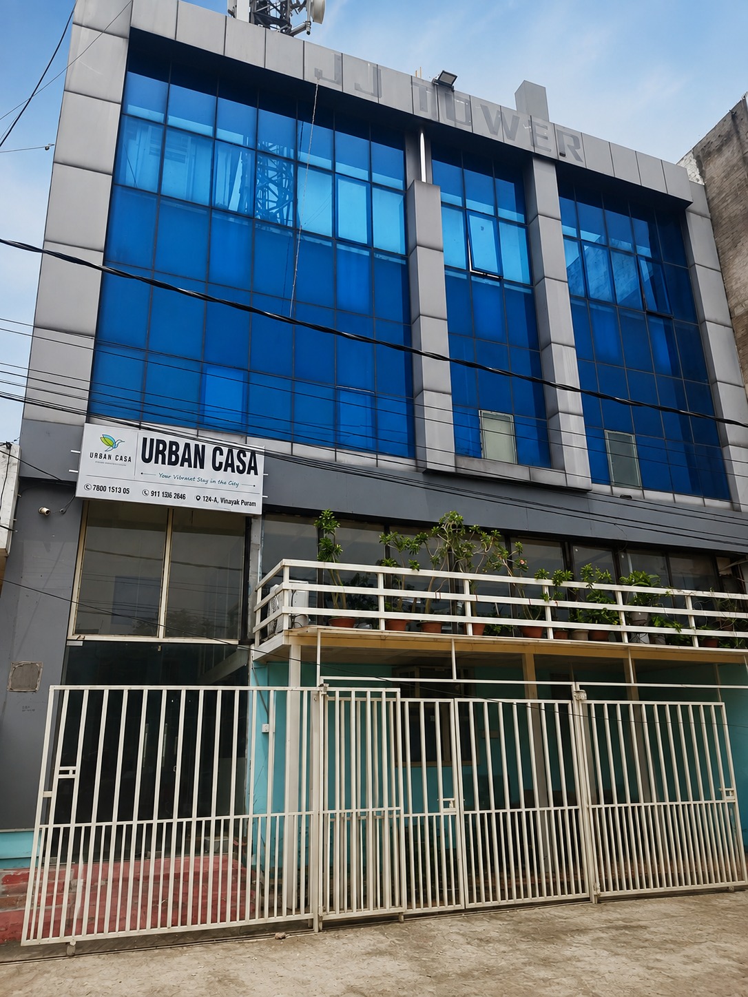 The blue-glass front of JJ Tower with the Urban Casa signboard