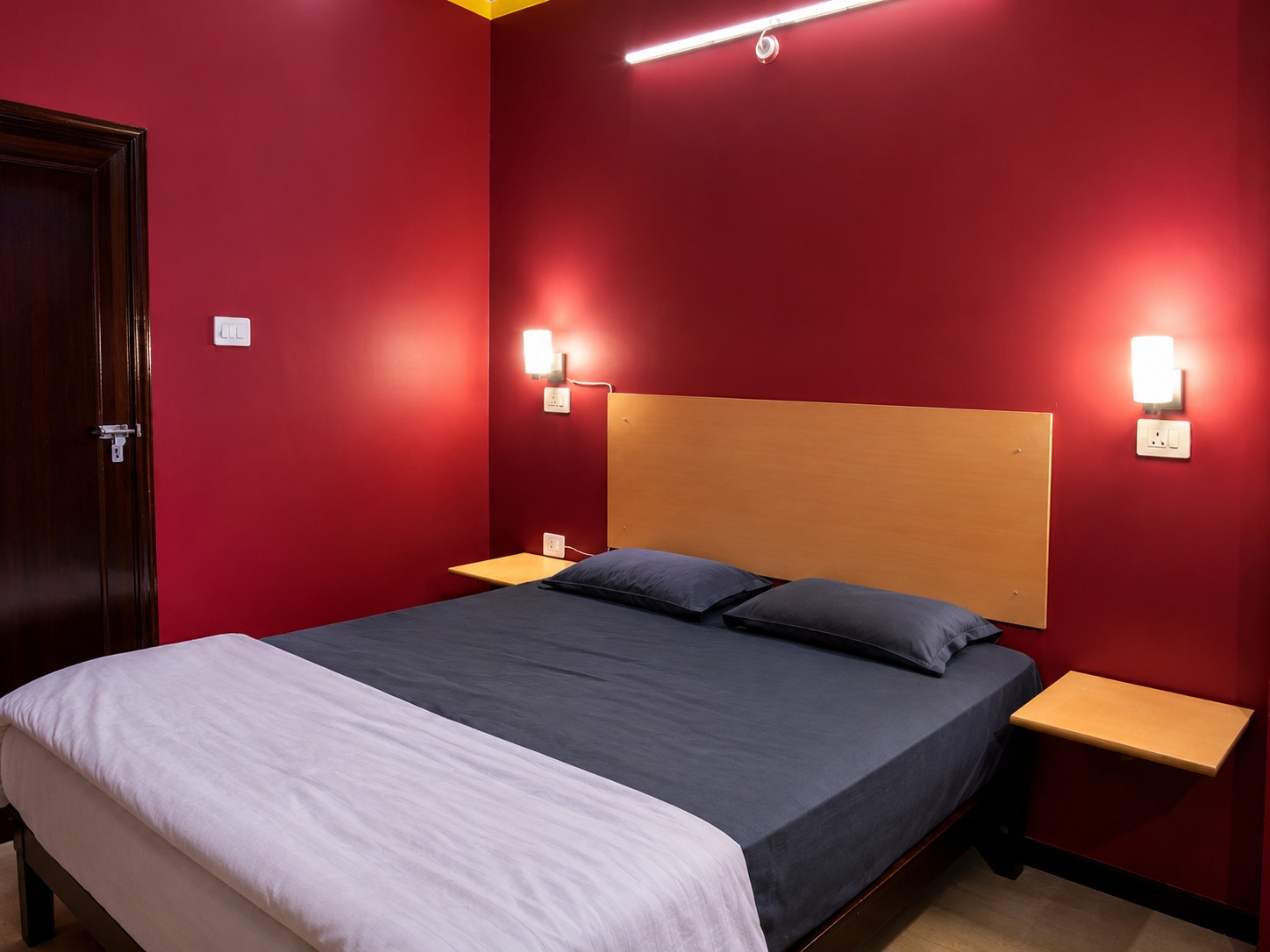 Classic room with crimson walls, a wooden headboard and bedside shelves
