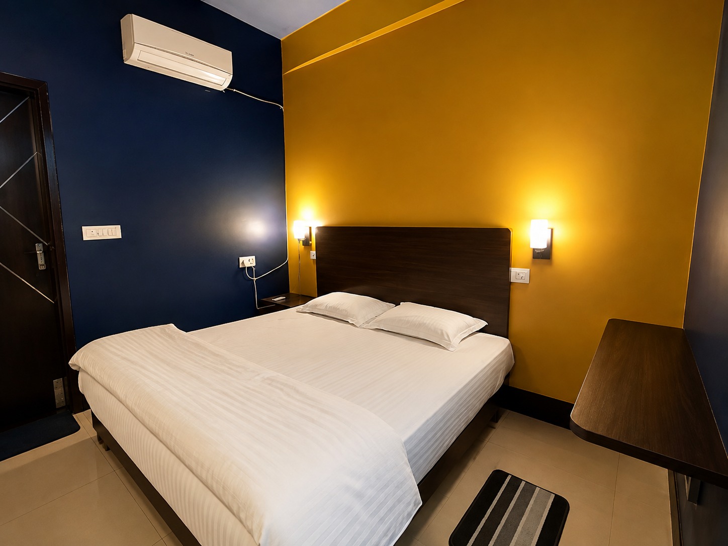 Delux room with a navy wall, mustard feature wall and dark wood headboard