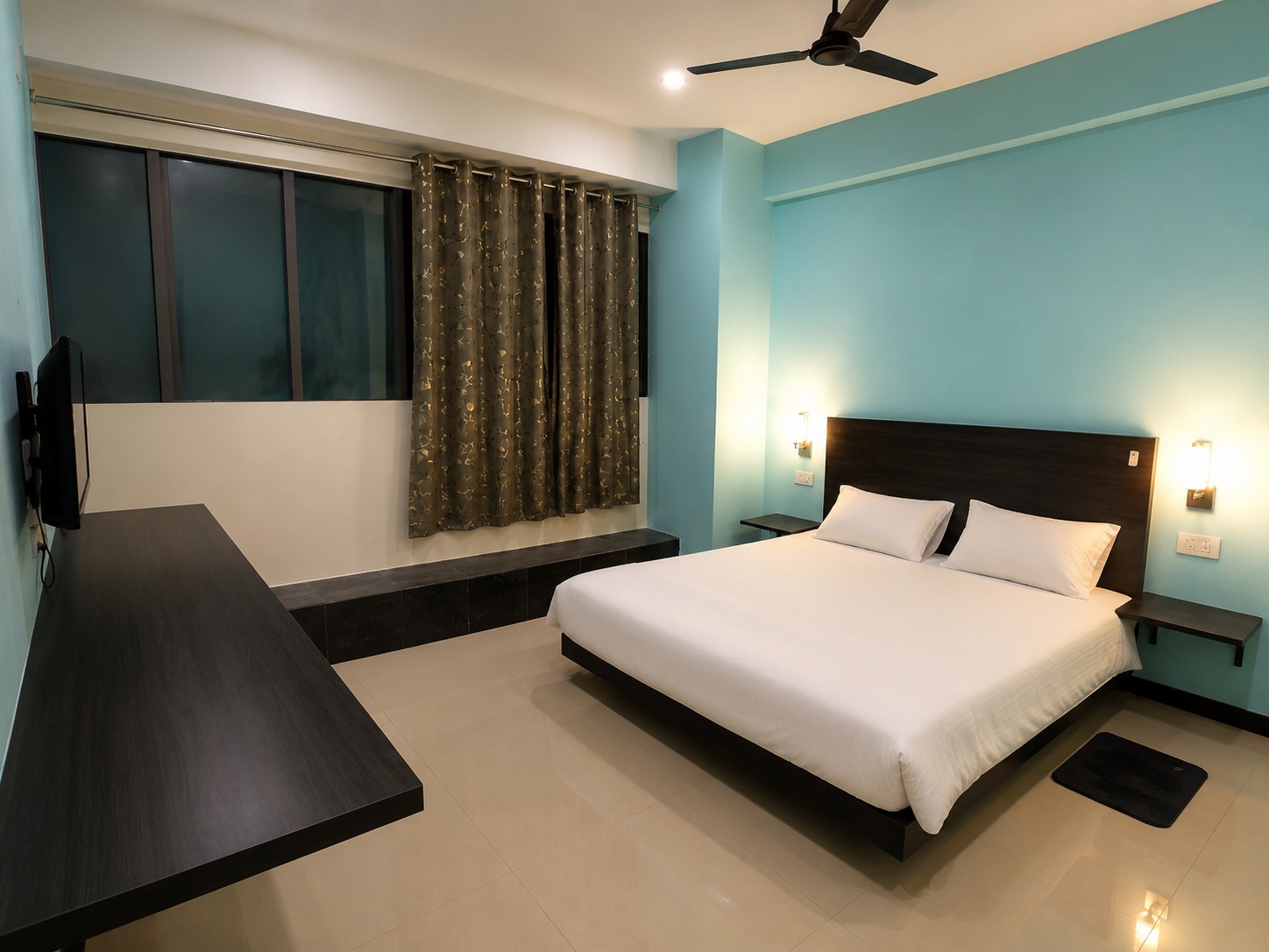 A premium room at Urban Casa with a teal wall, king bed and wall-mounted television